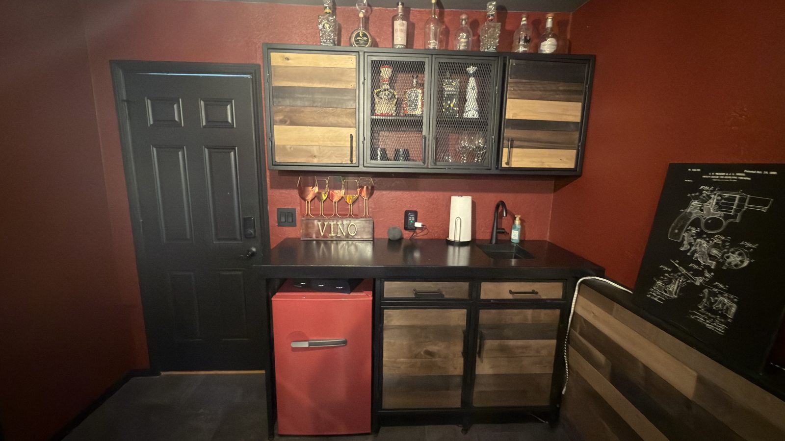 Finished wet bar: concrete top, sink, mesh-front upper cabinets, and reclaimed wood.